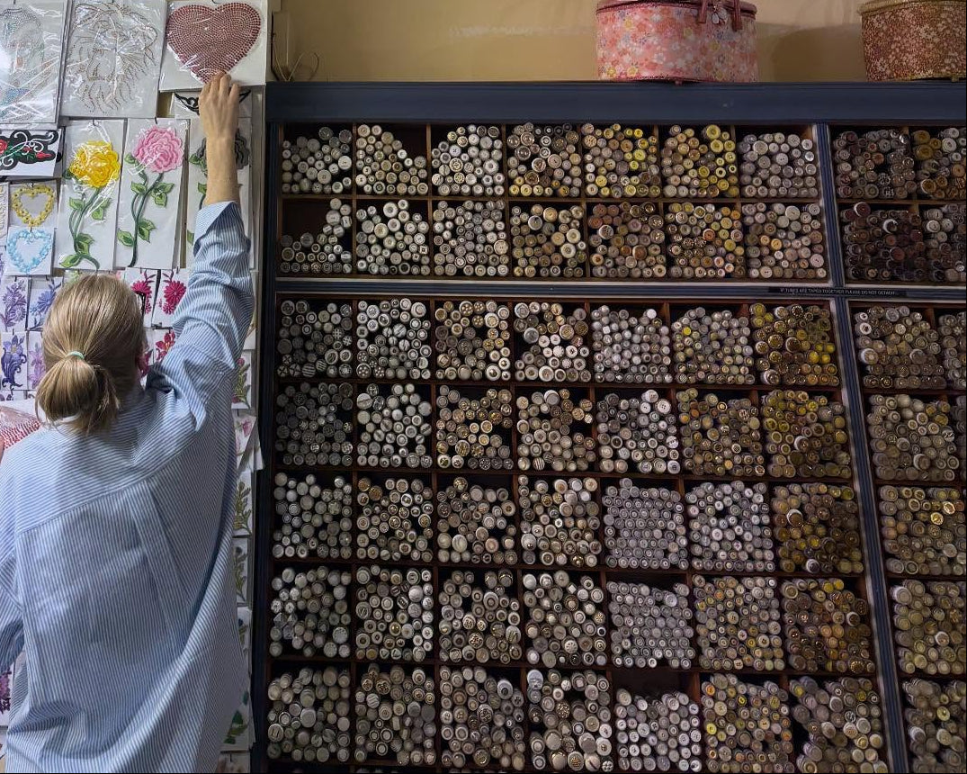 store worker with buttons and reaching for a rhinestone heart motif