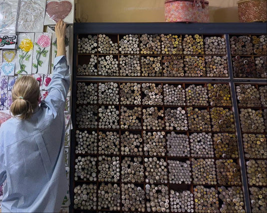 store worker with buttons and reaching for a rhinestone heart motif